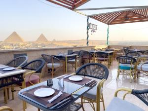 a restaurant with tables and chairs with pyramids in the background at Luxurious GEM and PYRAMIDS view in Cairo