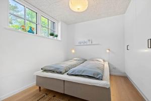 a bed in a room with white walls and a window at 8569-Grenaa-Kystvej-3-b in Grenå Strand