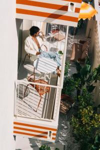 a woman sitting in a chair on a balcony at Riviera Hotel Menorca in Ciutadella