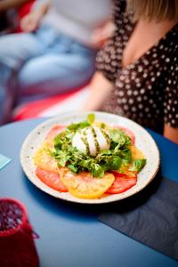 a plate of food with tomatoes and lettuce on a table at ClapClap Hôtel Strasbourg in Strasbourg