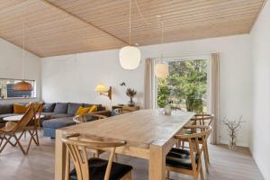 a dining room and living room with a wooden table and chairs at 8571-Grenaa-Kaprifolievej-20 in Grenå Strand