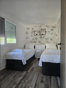 two beds in a bedroom with white walls and wood floors at Villa Mare Lux in Nea Fokea