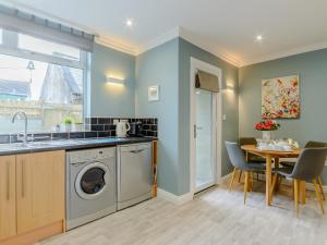 a kitchen with a washing machine and a table at High Haven in Amble