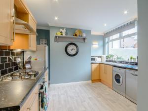 a kitchen with a clock on a blue wall at High Haven in Amble