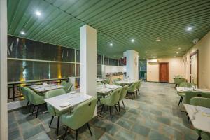 a dining room with tables and green chairs at Four Leaf Hotel Arjuna Manor, Varanasi in Varanasi