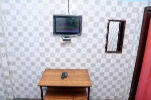 a television on a wall with a table and a remote control at SIU Elite INN in Chennai