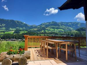 a wooden deck with a table and chairs and mountains at Chalet Moralee mit Whirlpool in Kitzbühel by ONE VILLAS in Kitzbühel