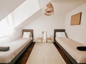 two beds in a room with white walls at Champagne getaway, spacious house in Épernay