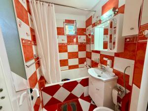 a bathroom with a red and white checkered wall at Apartament Arys 2 in Neptun