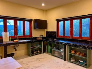 a kitchen with a counter and windows in a room at Spacious 2BR Mint house in Ban Nok