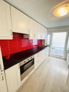 a kitchen with white cabinets and a red tile wall at ONS 2026 Economic Central accommodation in Stavanger +15 photos