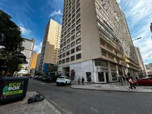 a tall building on a city street with cars at Confortavel Apartamento na Rua das Flores in Curitiba
