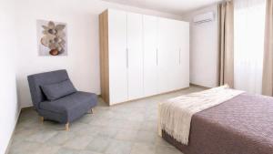 a bedroom with a bed and a blue chair at CASA NICOLAS 158 by SalentoAffitti in Neviano
