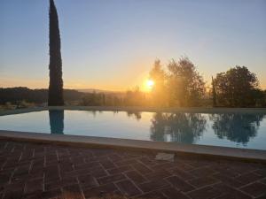 a swimming pool with the sunset in the background at Tenuta Il Tresto in Poggibonsi