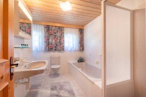 a bathroom with a sink and a tub and a toilet at Jägers Highlineblick in Breitenwang