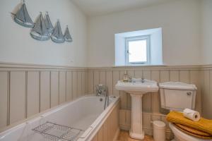a bathroom with a tub and a sink and a toilet at Ty Mor in Tenby +32 photos