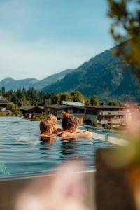 two people in the water in a swimming pool at Alpin Family Resort Seetal in Kaltenbach