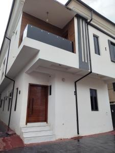 a white building with a wooden door and stairs at 5 bedroom apartment Magodo GRA in Sagisa