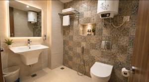a bathroom with a sink and a toilet and a mirror at YogMaya Regency in Shimla