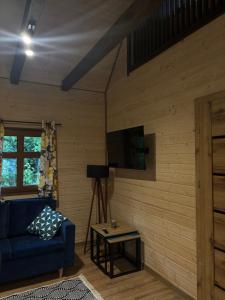 a living room with a blue couch and a table at Domki Stokrotka in Ruciane-Nida