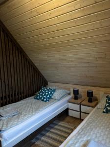 a room with two beds in a wooden cabin at Domki Stokrotka in Ruciane-Nida