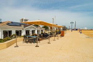a patio with tables and umbrellas on the beach at Wildflower Garden - Spacious Garden Apartment in Portsmouth