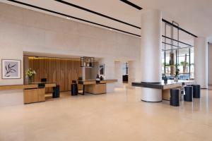 a lobby with tables and chairs in a building at Taghazout Bay Marriott Resort in Taghazout +145 photos