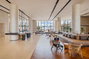 a lobby with a couch and chairs and windows at Taghazout Bay Marriott Resort in Taghazout