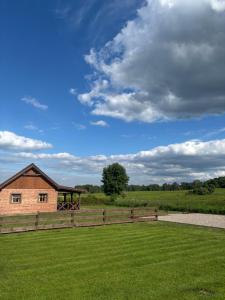 a brick building in a field with a fence at Domki Stokrotka in Ruciane-Nida