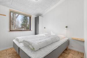 a large bed in a white room with a window at 8882-Glesborg-Kaervejen-5 in Fjellerup Strand