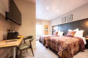 a hotel room with two beds and a desk at Tyn-y-Coed Inn in Betws-y-coed