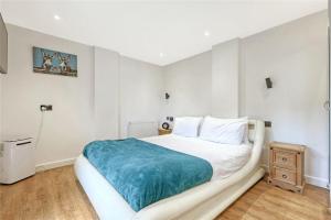 a white bedroom with a large bed with a blue blanket at The Stables in Great Horkesley