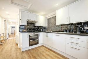 a white kitchen with white cabinets and a wooden floor at The Stables in Great Horkesley +8 photos