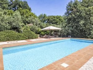 a swimming pool with an umbrella and trees at Villa Le More by Interhome in Penna in Teverina