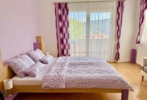 a bedroom with a bed and a large window at Apartmenthotel Karawankenblick - Free Parking in Pörtschach am Wörthersee
