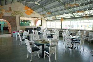 a dining room with tables and white chairs at Amorae Resort in Loni Khurd