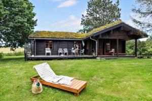 a log cabin with a deck and a chair in the yard at 84249-Knebel-Skraningen-13 in Knebel