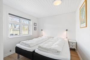 a bedroom with a bed with white sheets and a window at 8501-Grenaa-Ellevej-14 in Grenå Strand