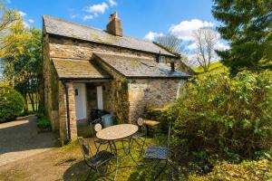 a table and chairs in front of a stone cottage at Red Squirrel Cottage, Hutton luxurious cottage in a rural setting 10 minutes to Ullswater 15 minutes to Keswick in Penruddock