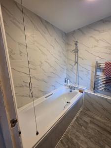 a white bath tub in a bathroom with marble walls at Olive & Ember - 1 Bed with private garden in Hythe +15 photos