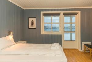 a bedroom with a white bed and two windows at Rorbuanlegget Svolvær Havn in Svolvær