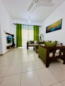 a living room with green curtains and a couch at Urban Nest Studio in Homagama