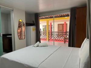 a bedroom with a large white bed and a balcony at Pousada Solar Maia Costa in Atins