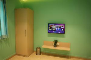 a room with a tv on a green wall at Amorae Resort in Loni Khurd