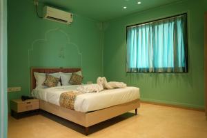 a bedroom with a bed with green walls and a window at Amorae Resort in Loni Khurd +7 photos