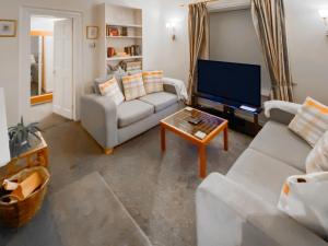 a living room with two couches and a tv at Elizabeth Lodge - Cottage in Alford