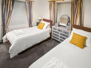 a bedroom with two beds and a mirror at Elizabeth Lodge - Cottage in Alford