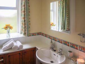 a bathroom with a sink and a mirror and a window at Elizabeth Lodge - Cottage in Alford
