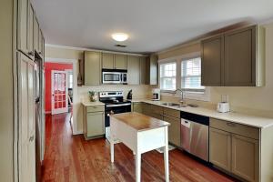 a kitchen with brown cabinets and a wooden floor at CB Sunshine Cottage in Carolina Beach