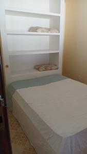 a white bed in a room with shelves at Casa Com 2 Quartos Barra Serinhaem - BA in Ituberá
